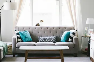 Photo with studio couch, coffee table, lamp, picnic basket, pillow and curtain