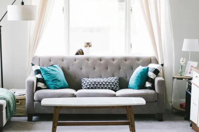 Photo with studio couch, coffee table, lamp, picnic basket, pillow and curtain