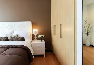 Photo with bed, cabinetry, nightstand, pillow, houseplant and lamp