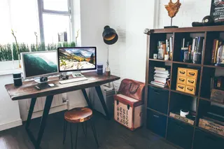 Photo with handbag, desk, cabinetry, television, trash bin/can and lamp
