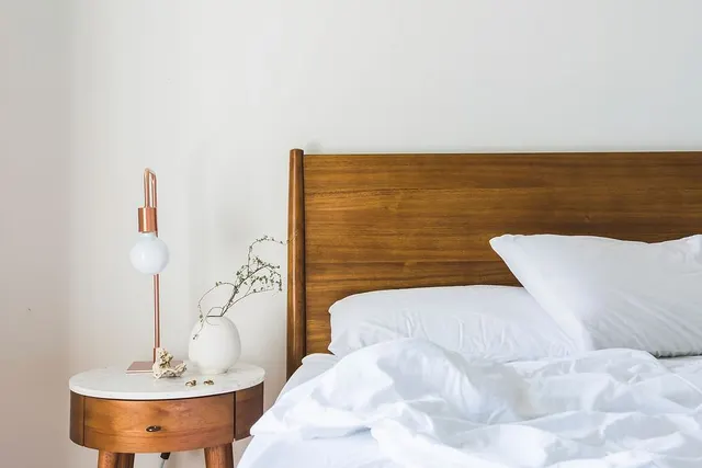 Photo with nightstand, bed, headboard and houseplant